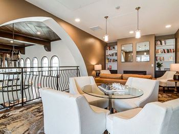 A modern living room with a glass table surrounded by white chairs.